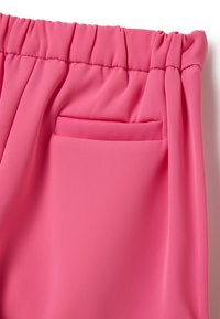 Pantaloni rosa con una texture morbida e liscia, vita elastica e una piccola tasca frontale piatta. Il design enfatizza una vestibilità casual.