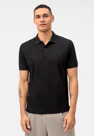 Polo noir en coton avec un col classique, des manches courtes et une patte de boutonnage à trois boutons. Texture lisse et design ajusté.