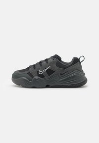 Zapatilla negra y gris con materiales de malla y ante, con punta redondeada, suela gruesa y logo de Nike en blanco en el lateral.