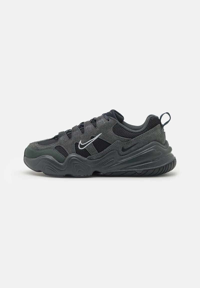 Zapatilla negra y gris con materiales de malla y ante, con punta redondeada, suela gruesa y logo de Nike en blanco en el lateral.