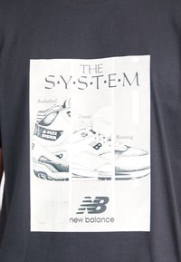 Tenisky New Balance označené pro basketbal, tenis a běh s textem "The System" a logem New Balance na tmavém tričku.