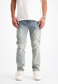 Lichtblauwe verstoorde jeans met een vervaagde afwerking, voorzien van scheuren, een rechte snit en een vijf-pocket ontwerp, gecombineerd met witte sneakers.