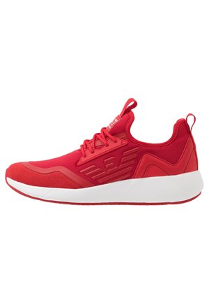 Baskets basses rouges avec lacets sur le devant, semelle en caoutchouc et logo en relief sur le côté, vues de la face extérieure sur fond blanc.