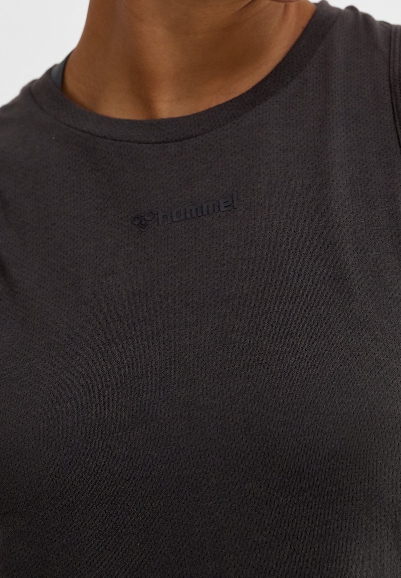 Débardeur sportif noir, en tissu respirant à surface texturée. Il présente un col rond et un logo en relief sur la poitrine.