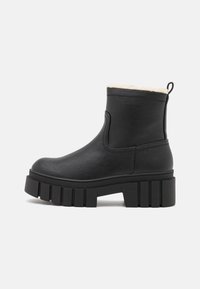 Bottines noires en cuir avec une finition texturée, semelle compensée et une doublure en fausse fourrure en haut, dotées d'une languette à l'arrière.