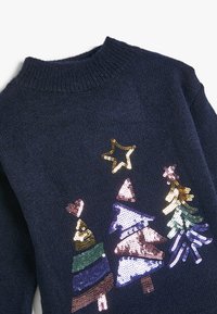 Granatowy sweter z rypsowym okrągłym dekoltem, z przodu zdobiony wielokolorowymi cekinami w kształcie choinek i gwiazdek bożonarodzeniowych.