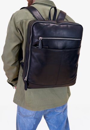 Zaino in pelle nera con una texture liscia, dotato di chiusura con cerniera superiore e tasca frontale con zip. Spallacci regolabili, forma rettangolare.