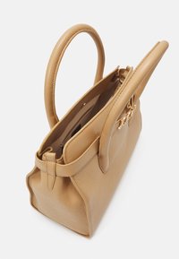 Borsa in pelle tan con due manici rotondi, forma strutturata e chiusura con zip. L'interno presenta ulteriori tasche per un'organizzazione ottimale.