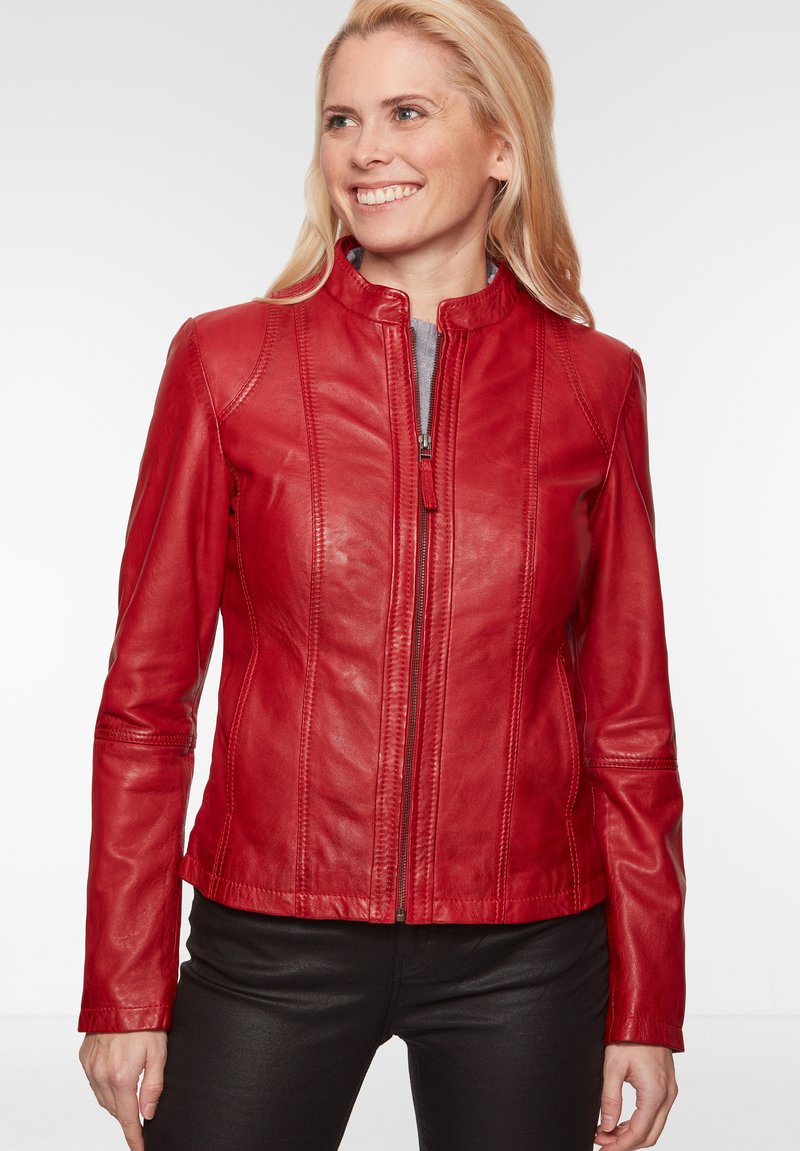 Rote Lederjacke mit Reißverschluss, hohem Kragen und vertikalen Nahtdetails. Weicher Stoff, taillierte Passform und lange Ärmel. Schwarze Hose.