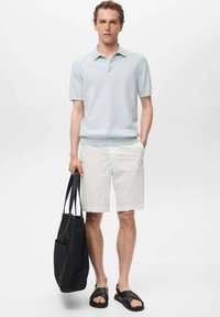 Tricou polo de culoare albastră deschisă, pantaloni scurți albi, sandale negre și o geantă de umăr neagră. Design simplu, cu mâneci scurte și croială lejeră.