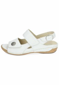 Sandale en cuir blanc avec des sangles ajustables, un accent métallique circulaire et une semelle en liège. Bout ouvert et découpes latérales pour une meilleure circulation de l'air.