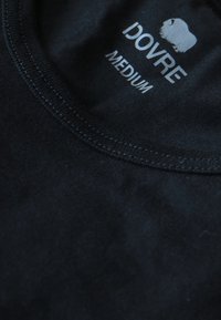 Sort bomulds T-shirt med rund hals, syede kanter og et mærke med teksten "DOVRE MEDIUM" i kontrasterende sølvfarve.