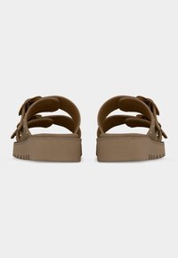 Paire de sandales à plateforme marron avec semelles épaisses et doubles brides réglables, vues de dos sur un fond uni.