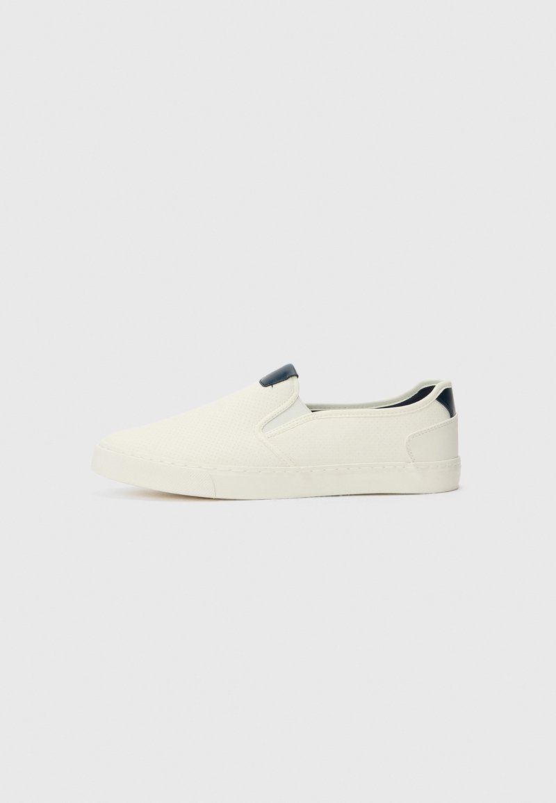 Könnyű, fehér szövetből készült slip-on cipők, texturált felülettel és kontrasztos, sötét sarokkal. Gumitalp a tapadásért.