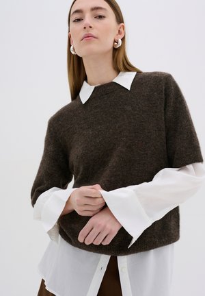 Brown wool sweater with a rounded neckline, layered over a white collared shirt featuring wide cuffs. Smooth texture and relaxed fit.