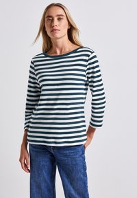 Gestreepte lange mouwen top in donkergroen en wit, gemaakt van zachte stof met een brede halslijn en een relaxte pasvorm, gecombineerd met blauwe jeans.