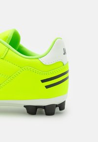 Neon groene voetbalschoen met een textuurleer bovenkant, witte hielaccenten en zwarte strepen. Heeft verhogingen voor grip.