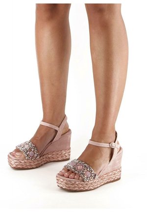 Sandales compensées en daim rose avec une semelle en jute tressé, présentant une sangle ornée de perles avec des motifs géométriques et une sangle de cheville réglable.