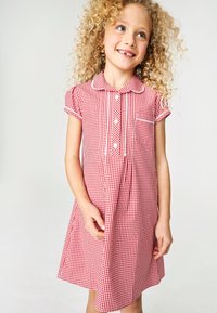 Vestito a quadretti rosso e bianco con maniche corte, scollo con colletto, chiusura frontale con bottoni e una piccola tasca sul petto.