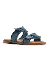 Sandali in denim con elementi annodati doppi. Materiale blu chiaro con bordi sfrangiati. Suola piatta di colore marrone chiaro. Design open-toe.