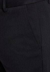 Schwarze Stretch-Hosen mit glatter Textur. Sie verfügen über eine flache Vorderseite, Seitentaschen und einen eng anliegenden Bund für Komfort.