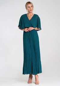 Turkusowa, plisowana sukienka maxi z krótkimi, falbaniastymi rękawami oraz dekoltem w kształcie litery V, wykonana z lekkiego materiału. Posiada ściągnięty w talii krój oraz zwiewny dół.