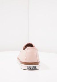 Sneaker in tela rosa con un design a profilo basso, suola in gomma marrone e dettagli bianchi. Logo stampato sul tallone. Texture liscia.