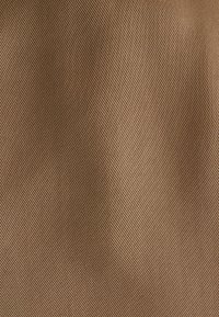Tissu marron texturé avec un motif rayé diagonal, présentant une surface lisse et un léger éclat. Idéal pour l'ameublement ou la mode.