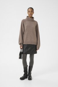 Brown knit sweater with a high collar, paired with a black leather skirt and gray leggings. Black knee-high boots and a small black handbag.