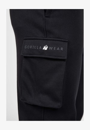 Zwarte cargo broek met een opvallende patchzak en het "GORILLA WEAR" logo. Materiaal is zacht en gestructureerd, met stikselaccenten.