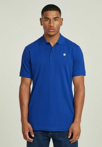 Polo shirt blu realizzato in tessuto liscio con pattina a tre bottoni, maniche corte e un piccolo logo sul lato sinistro del petto.