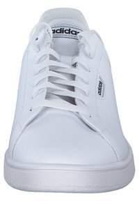 Zapatillas deportivas blancas con parte superior sintética lisa, sistema de lazado con seis ojales, suela de goma texturizada y pequeño detalle de logo en el lateral.