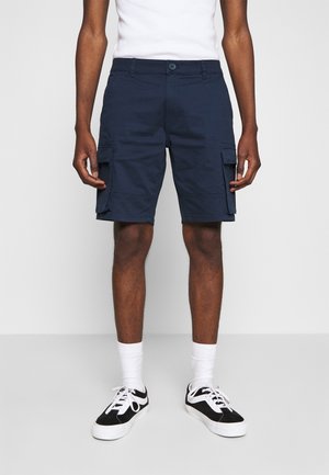 Navy blue cargo shorts made of cotton, featuring side pockets, a button closure, and a relaxed fit, paired with black and white sneakers.