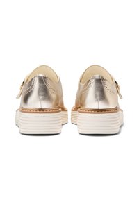 Metalliska guldskor med en slät yta, med en sydd design och en vit räfflad sula. Utrustning inkluderar en liten spänndetalj.