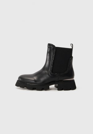 Bottine en cuir noir avec semelle épaisse, panneau latéral élastique, languette de traction et décoration sur les bords et la semelle.