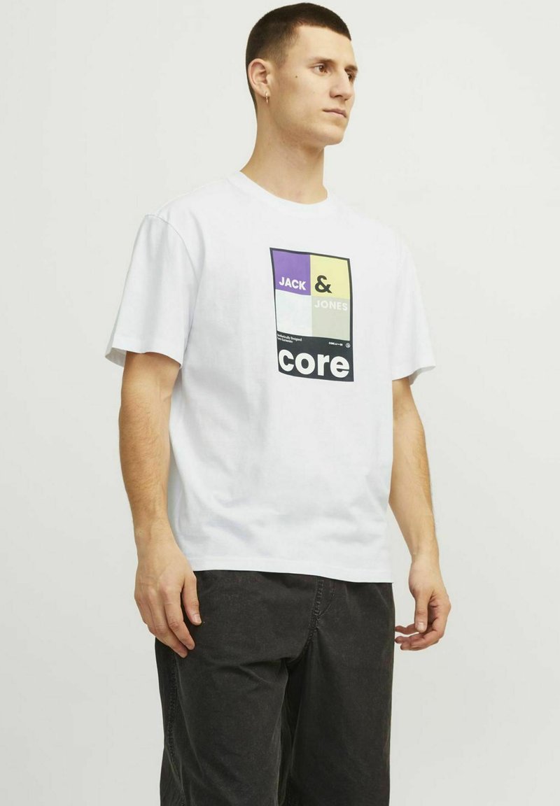 Baltas medvilnės marškinėliai su daugiaspalvėmis grafikomis, ant kurių užrašyta "JACK & JONES" ir "core" priekyje. Trumpomis rankovėmis, laisvas kirpimas.