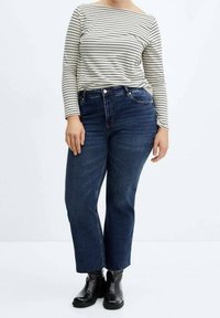 Haut à manches longues rayé crème et marine ; jean droit bleu foncé ; bottines noires ; tissu lisse et silhouette raccourcie.