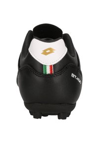 Scarpa da calcio nera con accentuazione bianca sul tallone, logo oro e strisce della bandiera italiana. Caratterizzata da pelle testurizzata e tacchetti stampati.