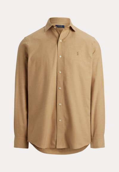 Camicia a maniche lunghe marrone chiaro con colletto a bottoni, caratterizzata da un logo sul petto e un orlo dritto con bordi arrotondati.