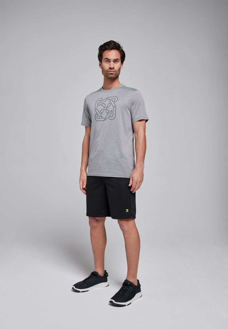 Grijze t-shirt met korte mouwen en een zwart geometrisch patroon, gecombineerd met zwarte shorts en zwarte sportieve schoenen met een gele logo.