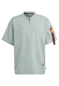 Hellgrünes Kurzarmhemd mit einem Halb-Reißverschlusskragen, ausgestattet mit einer Seitentasche mit orangefarbenem Riemen und einem kleinen Logo am Saum.