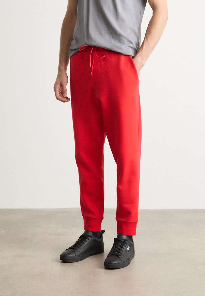 Rode sweatpants met een verstelbare taille, geribbelde boorden en een geborduurd logo op de dij. Gecombineerd met zwarte sneakers.
