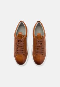 Brune lærersneakers med rund tå, flade hvide gummisåler og snørelukning, der har tekstureret tunge og syede detaljer.