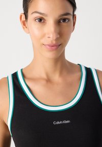 Crna rebrasta majica bez rukava s akcentima u tirkiznoj i bijeloj boji, sa okruglim izrezom i izvezenim logotipom "Calvin Klein" u bijeloj boji.