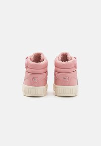 Różowe sneakersy typu high-top z podszyciem z sztucznego futra, wyściełanym kołnierzem i teksturowaną gumową podeszwą. Posiadają logo z boku oraz regulowany pasek.