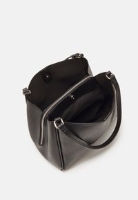 Sac à main en cuir noir avec doubles anses, doté d'un compartiment central zippé et d'une fermeture pression à l'intérieur d'une section principale ouverte.