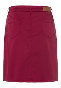Jupe en coton bordeaux avec une coupe droite, deux poches arrière et une étiquette en cuir sur la taille. Texture lisse et design simple.