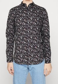 Camicia nera con bottoni dallo schema floreale in tonalità bianche, rosse e blu. Presenta un colletto classico e maniche lunghe con orlo curvo.