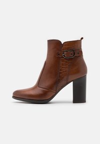 Hnědé kožené kotníkové boty s vysokým blokovým podpatkem, s texturovanou boční částí a dekorativní sponou. Hladký povrch a zaoblená špička.