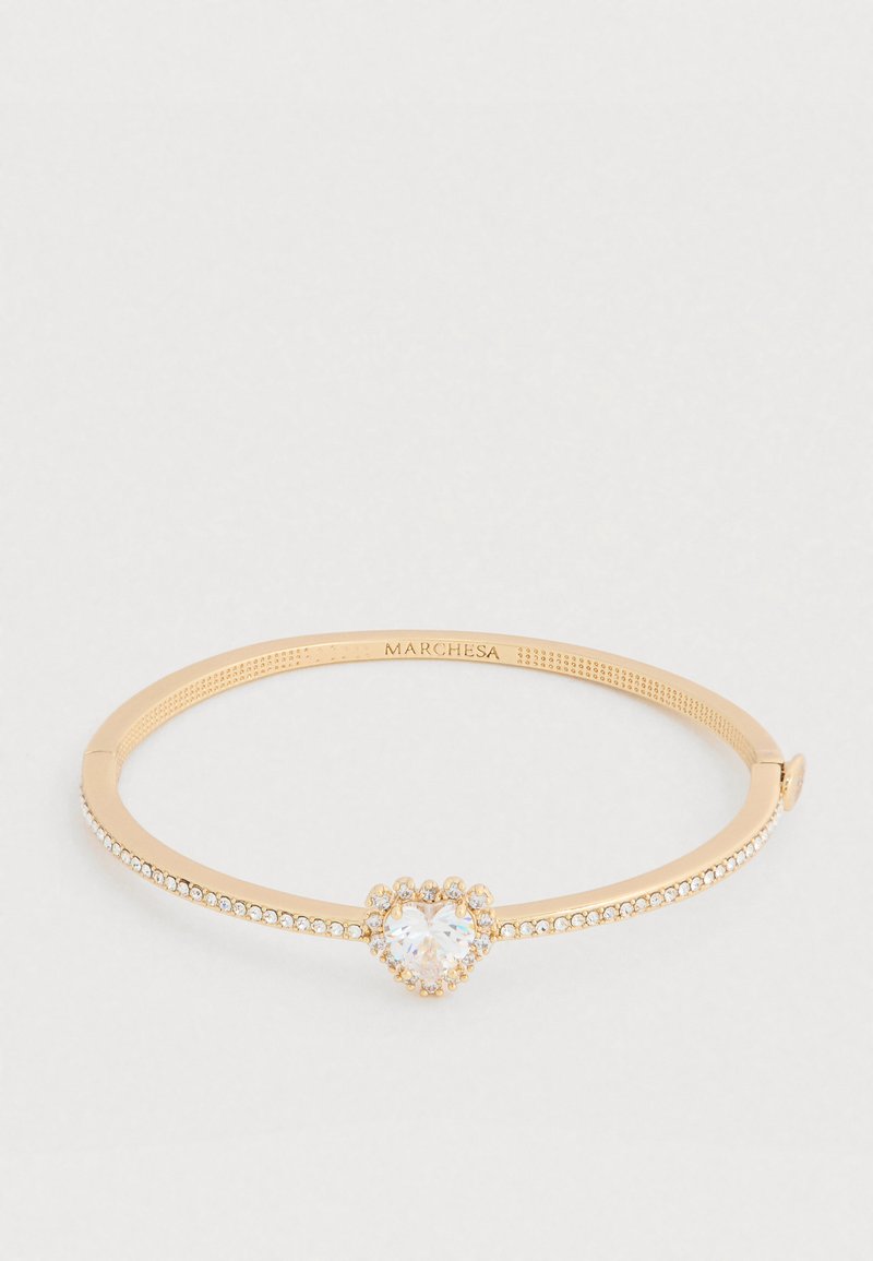 Kuldne käevõru, millel on südamekujulise tsirkooniumtsentri ja väikeste läbipaistvate kristallidega kaunistatud riba ning sile tekstuurne viimistlus.